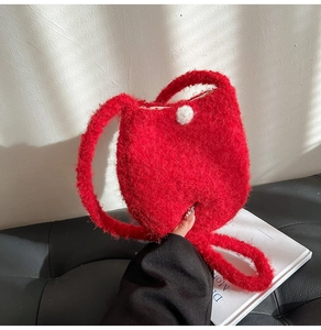 Detailed view of red faux fur bucket bag with white pom-pom clasp and soft texture