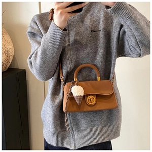 Detail einer braunen Lederhandtasche mit goldenem Drehverschluss und Plüsch-Anhänger