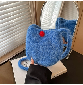 Detailed texture of blue plush knit bucket bag with a decorative red faux fur pom-pom
