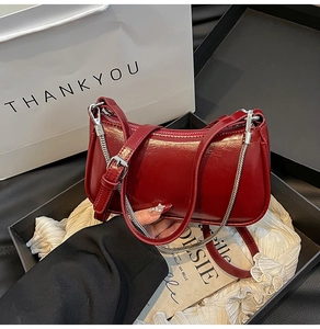 Détail du sac bandoulière en cuir bordeaux avec chaîne argentée dans un coffret cadeau