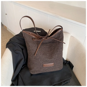 Deep brown textured tweed bucket bag with leather drawstring and elegant shoulder strap