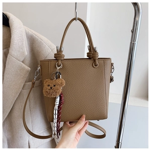 Detail view of khaki bucket bag with lychee texture leather and plush bear charm
