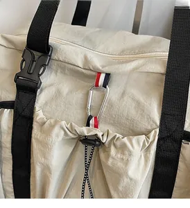 Dettaglio della borsa in nylon bianco sporco con fibbia nera e cinturino a righe