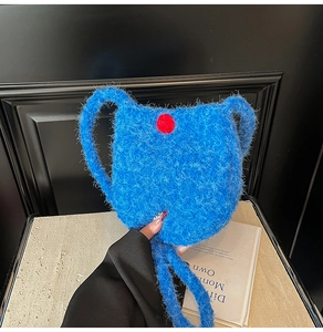 Close-up of blue plush bucket bag featuring a vibrant red pom-pom and soft fur texture
