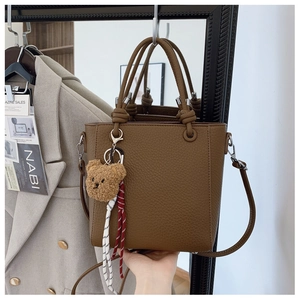 Detailed texture of brown lychee grain bucket bag with cute plush bear pendant