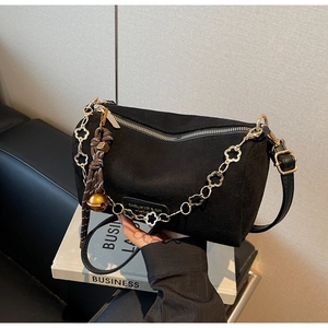 Dettaglio borsa Boston in camoscio nero con catena floreale dorata e nappa decorativa