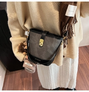 Close-up of a two-tone bucket bag with suede texture and gold metal buckle detail