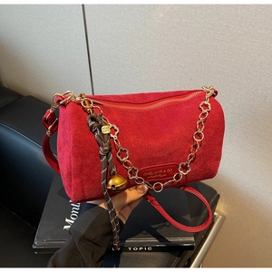 Dettaglio di una borsa a cilindro in camoscio rosso con catena floreale e campanello