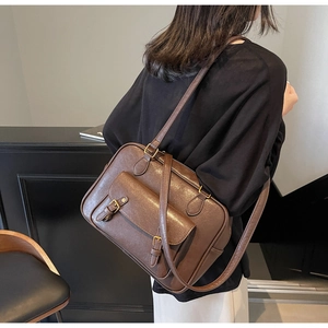 Side view of a vintage dark brown leather crossbody bag with double buckle front pocket