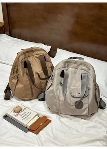 Detail of multi-pocket nylon backpacks in coffee and beige with dual-carry handles
