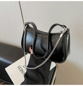 Details der schwarzen glänzenden Baguette-Tasche mit Silberkette und Lacklederstruktur