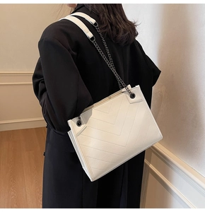 Detail of white leather shoulder bag with V-shaped quilting and black metal chain strap