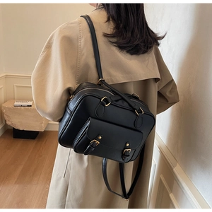 Detail view of high-quality black PU leather backpack with gold buckles worn by a model