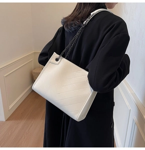 Detail of white faux leather tote with V-quilted stitching and metal chain strap