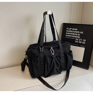 Dettaglio borsa da viaggio in nylon nero con nastro tricolore e moschettone metallico