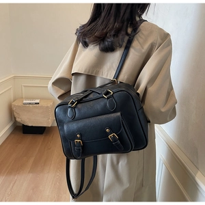 Detail view of large capacity black PU leather backpack with vintage metal buckles on trench coat