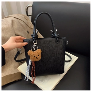 Detail of black lychee grain bucket bag with teddy bear charm and knot handle