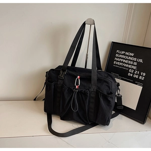Dettaglio della borsa tote in nylon nero con design multitasche e nastro tricolore