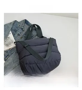 Gros plan d'un sac matelassé gris foncé avec des anses larges en tissu et texture en nylon