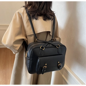 Detail of vintage black PU leather backpack with gold buckles and dual strap design