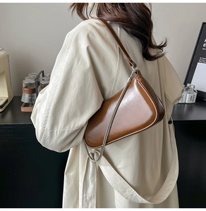 Detailaufnahme der dunkelbraunen halbmondförmigen Tasche aus Glanzleder mit Metallkette