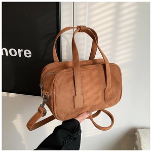 Detail of brown matte texture handbag with vertical stitching and silver metal zipper