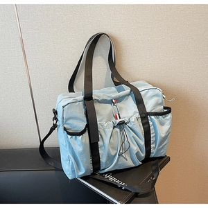Dettaglio borsa da viaggio in nylon celeste con tasca a coulisse e nastro tricolore sport