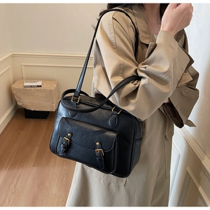 Detail of black PU leather bag with vintage gold buckles and fine texture on front pocket