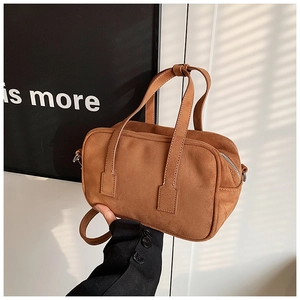 Detail showing the matte texture and fine stitching on a brown crossbody bag