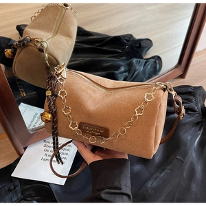 Vista dettagliata di una borsa a cilindro in camoscio marrone con catena dorata a petali