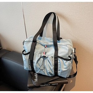 Dettaglio borsa da viaggio azzurra con tasca frontale a coulisse e tracolla regolabile