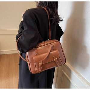 Close-up of retro brown briefcase bag with metallic double buckle flap on a model