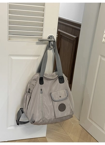 Detail view of khaki nylon tote bag with functional pockets and circular logo design