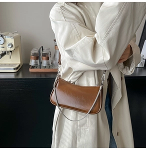 Detail der vintage braunen glänzenden Ledertasche mit Silberkette und schickem Riemen