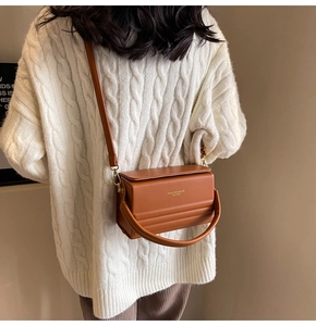 Brown leather crossbody bag with quilted texture shown on an off-white knit sweater