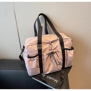 Dettaglio borsa da viaggio in nylon rosa con tasca a coulisse e cinturini tricolore