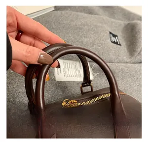 Detail of brown vintage crossbody bag showing golden metal double zippers and handle texture