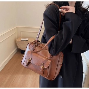 Detail of vintage brown leather underarm bag with double buckle straps and glossy finish