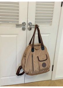 Detail of khaki nylon bag with brown webbing handles and functional side pockets