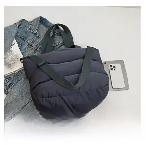 Détail du sac cabas matelassé gris foncé en nylon avec sangle verte et texture rembourrée