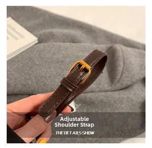 Detail of adjustable dark brown leather shoulder strap with gold-tone metal buckle