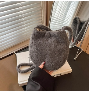 Detailed view of dark grey knit bucket bag with button closure and soft fuzzy texture