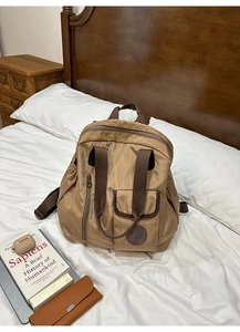 Detail of khaki nylon backpack with wet-dry separation and premium round logo on white bed