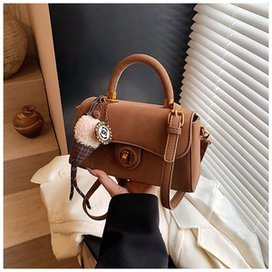 Detailansicht der braunen Handtasche mit goldenem Drehverschluss und Eiscreme-Anhänger