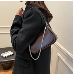 Detailansicht der dunkelbraunen, glänzenden Ledertasche mit silberner Kettenverzierung