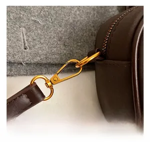 Detail showing high-quality gold metal hook and dark brown leather shoulder strap