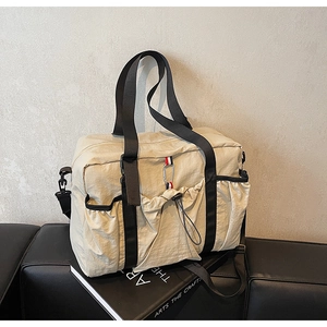Dettaglio della grande borsa da viaggio in tela beige con tasche laterali e scomparto frontale