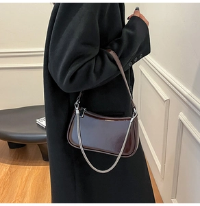 Detail einer dunkelbraunen Lackleder-Schultertasche mit silberner Gliederkette