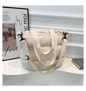 Détail d'un sac cabas matelassé crème avec boucles noires et bandoulière réglable