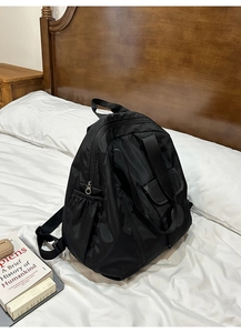 Detail of black nylon backpack with magnetic flap pocket and silver-tone hardware